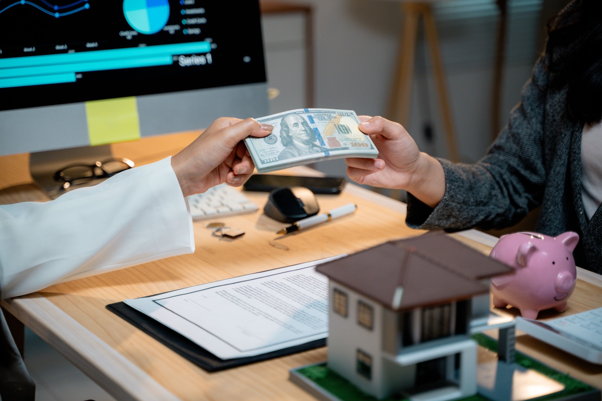 Real estate agent receiving dollar banknotes from client after signing contract for house purchase, investment, mortgage, and property